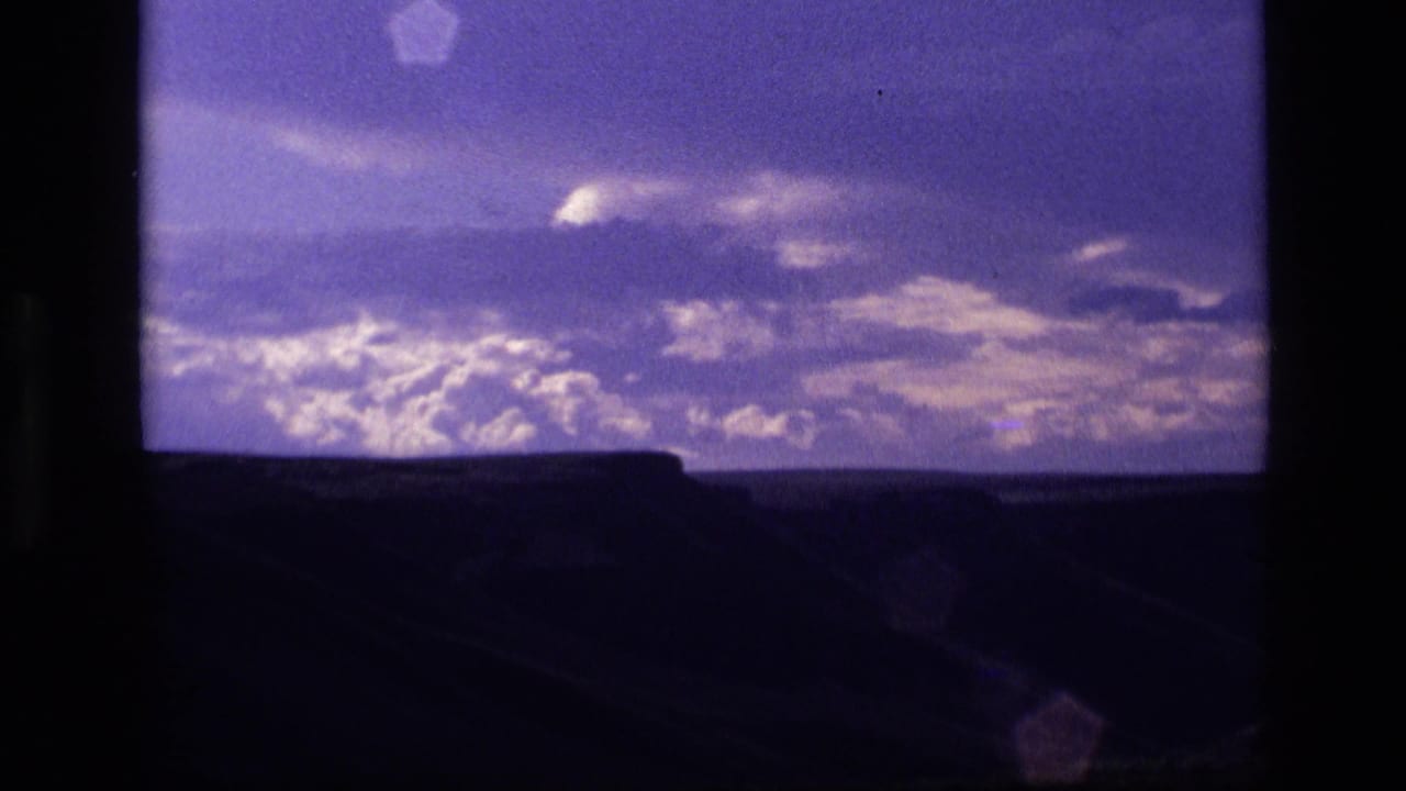 1972 Idaho 8mm frame with layered twilight clouds and a dark landscape edge below.
