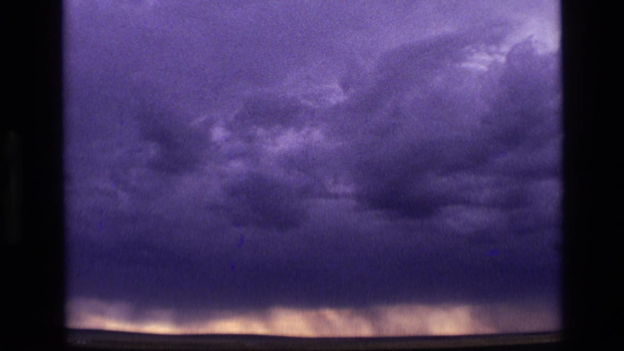 Dark storm clouds over a low glowing horizon with purple-blue 8mm color.