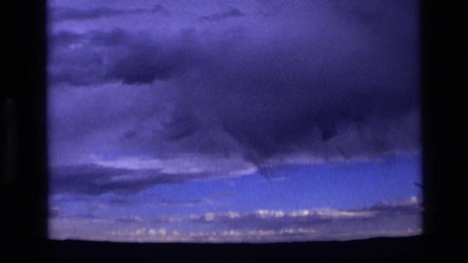 1972 Idaho 8mm view of heavy storm clouds looming above a faint, low landscape horizon.