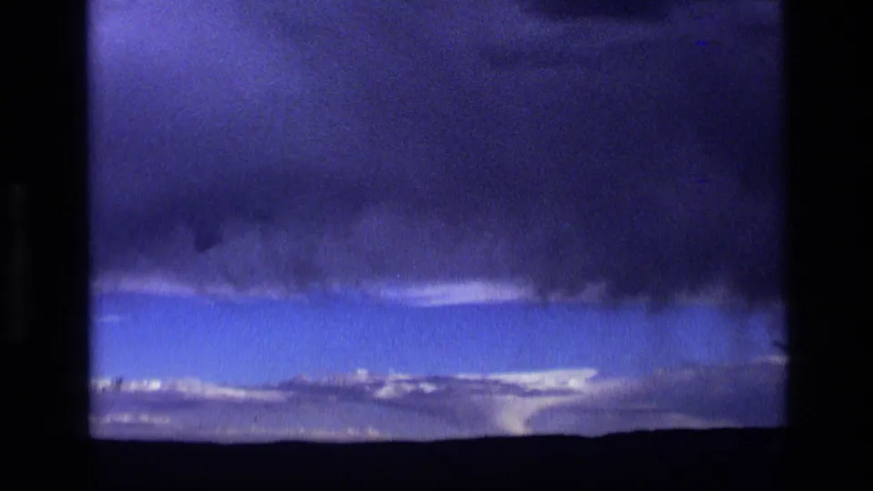 1972 Idaho 8mm frame with looming dark clouds, a blue-purple sky band, and a low desolate horizon.