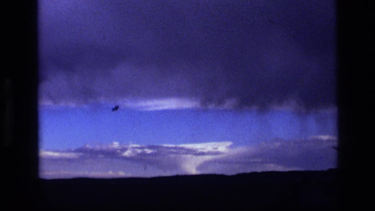 1972 Idaho 8mm frame showing dark storm clouds over a low rural horizon beneath a blue-purple sky.