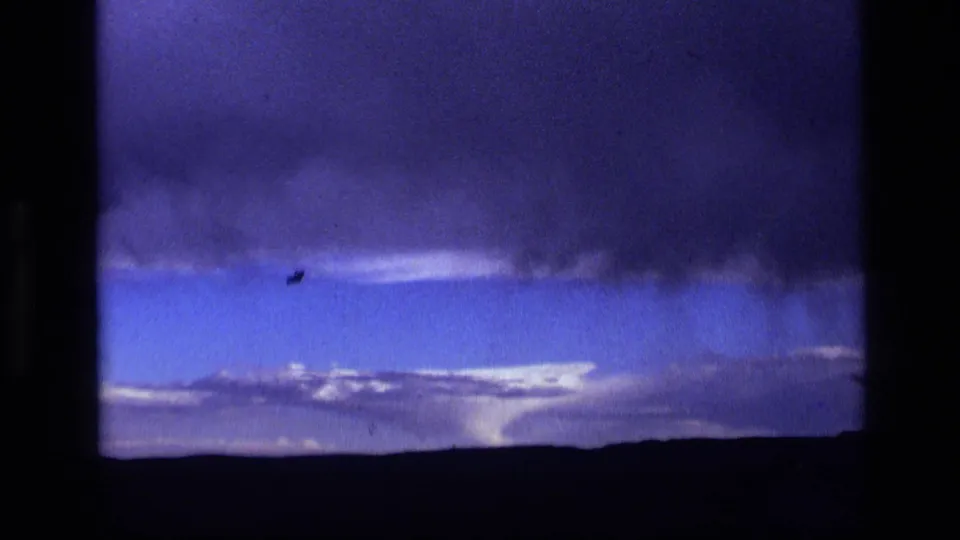 1972 Idaho 8mm frame showing dark storm clouds over a low rural horizon beneath a blue-purple sky.