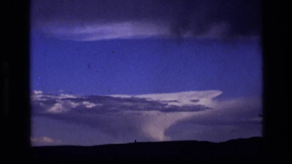 1972 Idaho storm footage showing a funnel-like lowering beneath a dark cloud mass over open land.
