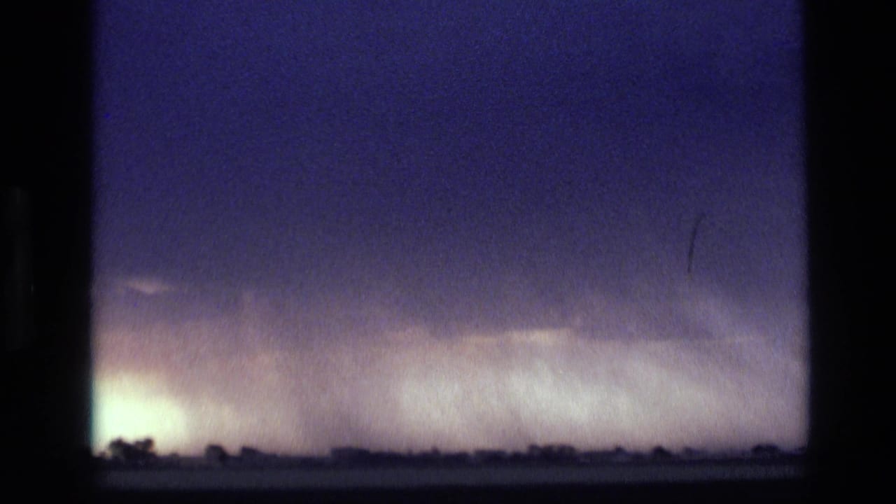 1972 Idaho 8mm frame showing a dark purple storm front over a low rural horizon with rain bands in the distance.