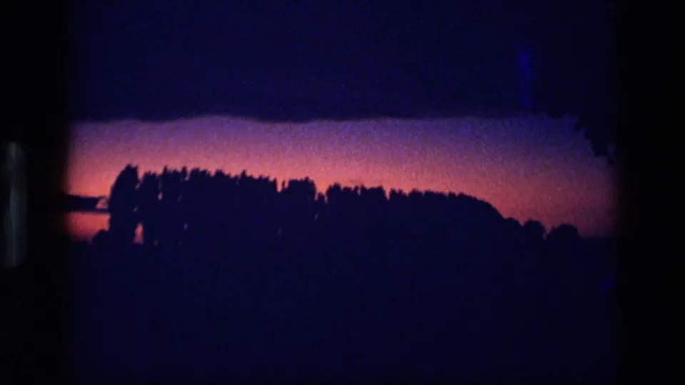 1972 Idaho 8mm frame showing a darker treeline as the purple sunset fades into blue night.