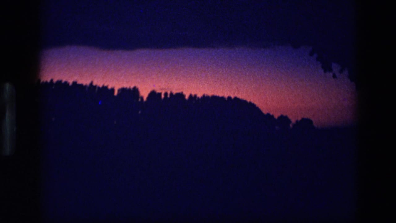 1972 Idaho 8mm frame showing a dark wooded horizon silhouetted against a red-magenta and deep purple twilight sky.