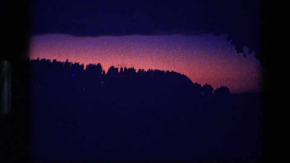 1972 Idaho 8mm frame showing a dark wooded horizon silhouetted against a red-magenta and deep purple twilight sky.