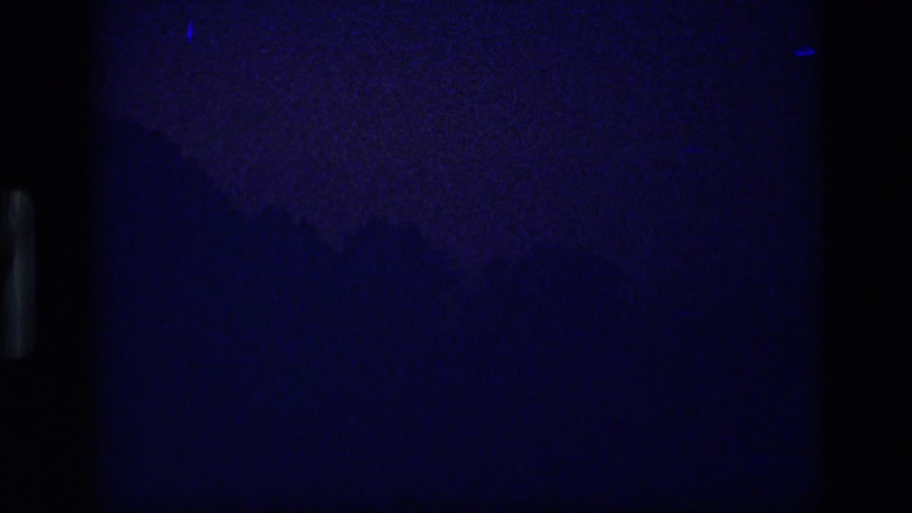 Very dark blue night frame with faint landscape shapes.