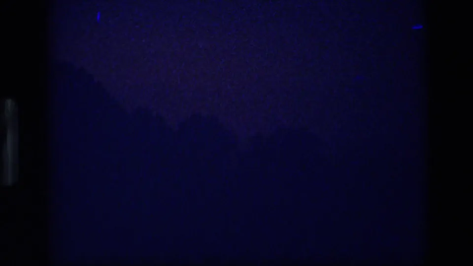 Low-light 8mm frame from the Idaho sequence with faint blue landscape forms after dusk.