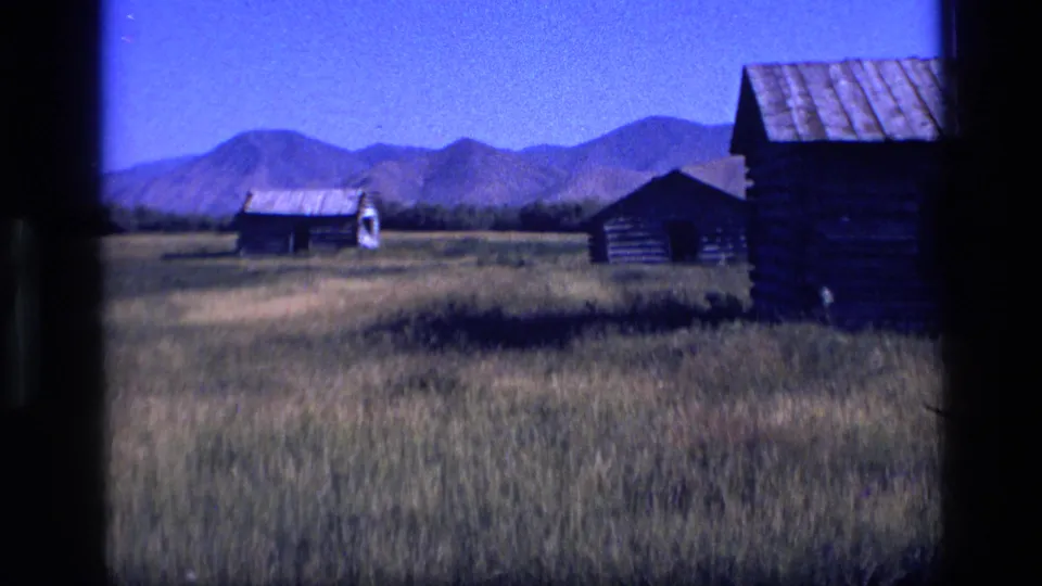 Daylight 8mm view of Idaho prairie cabins set against a distant mountain range.
