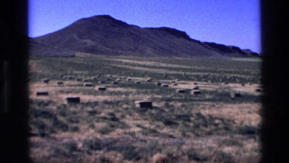 1972 Idaho cemetery landscape with scattered low grave markers and a hill rising in the background.