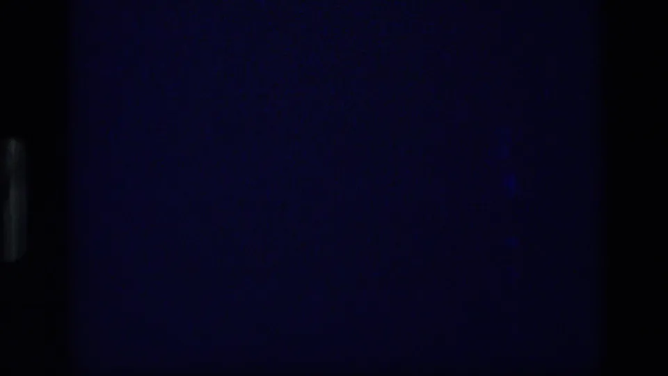 Underexposed 8mm frame from the 1972 Idaho clip, with little visible detail beyond dark blue film tone and projector edges.