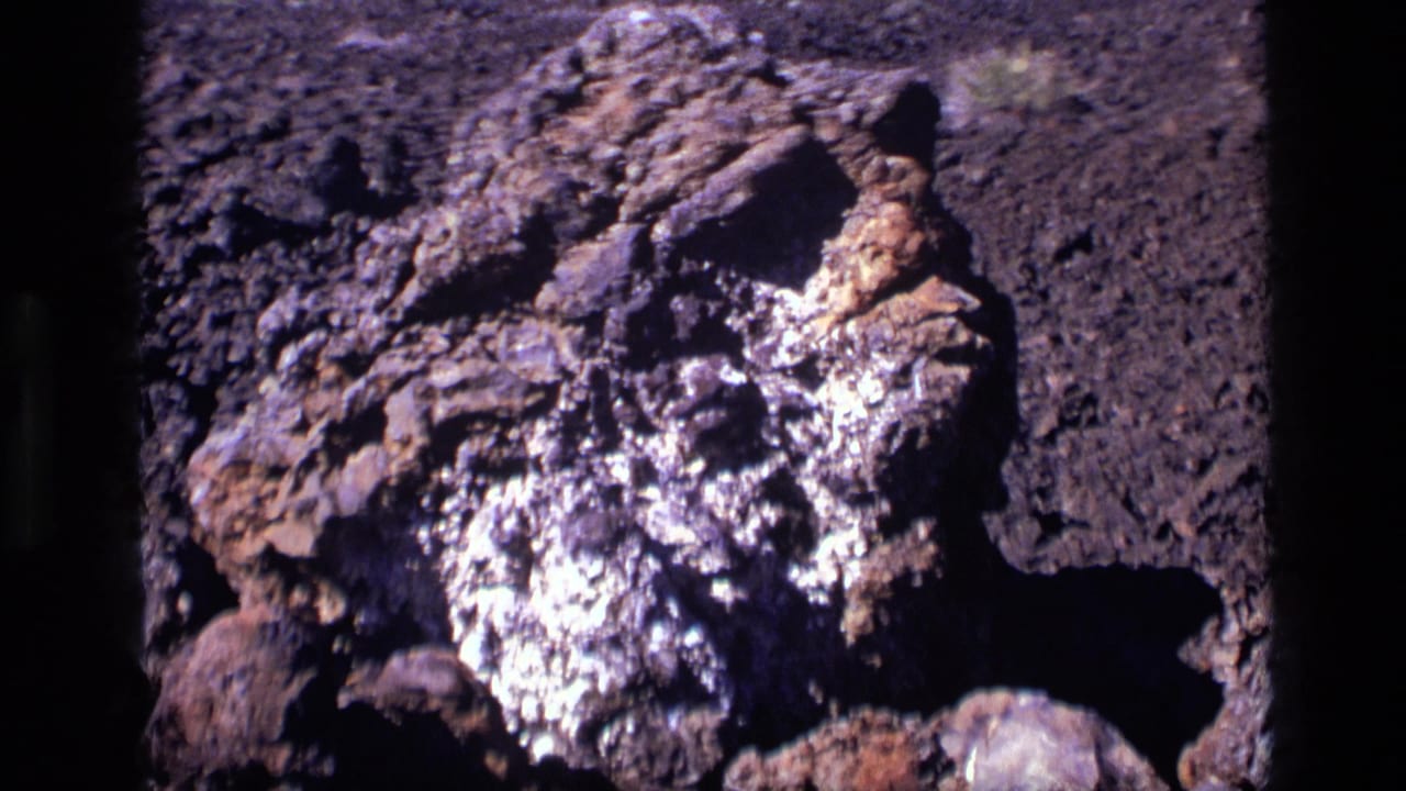 1972 Craters of the Moon view of a rough lava-rock formation, framed closely with open volcanic ground behind it.