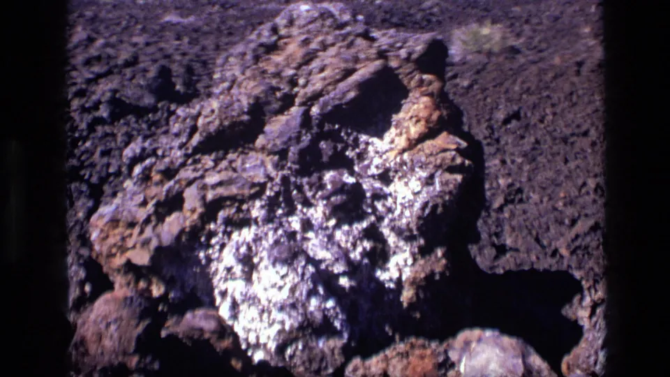 1972 Craters of the Moon view of a rough lava-rock formation, framed closely with open volcanic ground behind it.