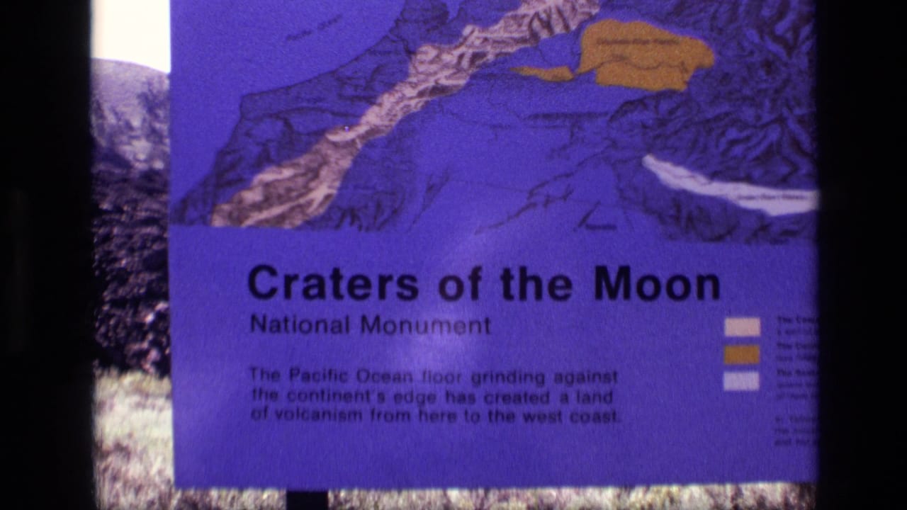 Close 1972 Idaho home-movie view of the Craters of the Moon National Monument sign, with map graphics and explanatory text visible.