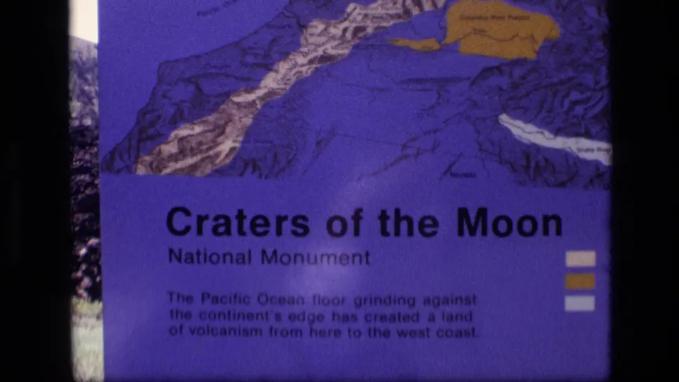 Tightly framed 8mm view of the Craters of the Moon National Monument sign, emphasizing the printed title and map artwork.