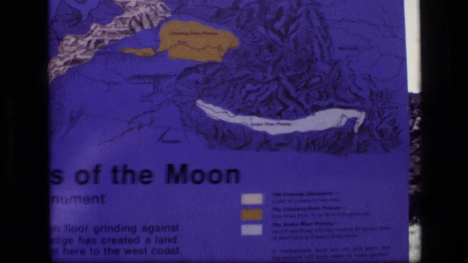 Cropped 1972 Idaho 8mm frame showing the lower part of the Craters of the Moon sign, including map legend blocks and text.