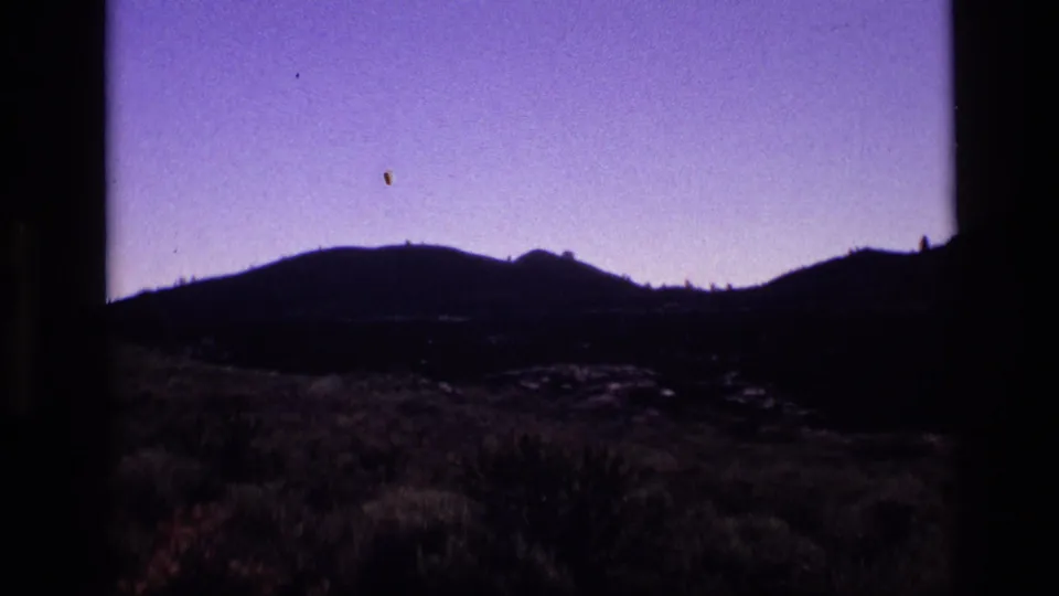 1972 Idaho 8mm frame showing a violet evening sky above silhouetted mountains and low desert vegetation.