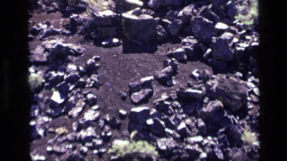 Close 1972 Idaho 8mm view of a circular bare patch surrounded by larger stones, with sparse brush at the edges.