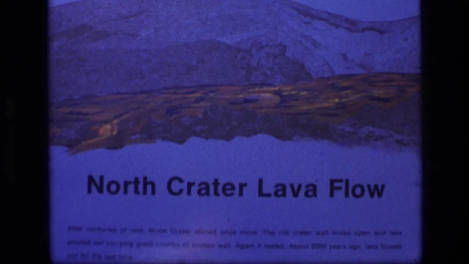 Final 8mm frame shows the Idaho park sign titled North Crater Lava Flow, with illustrated volcanic terrain and visible film texture.