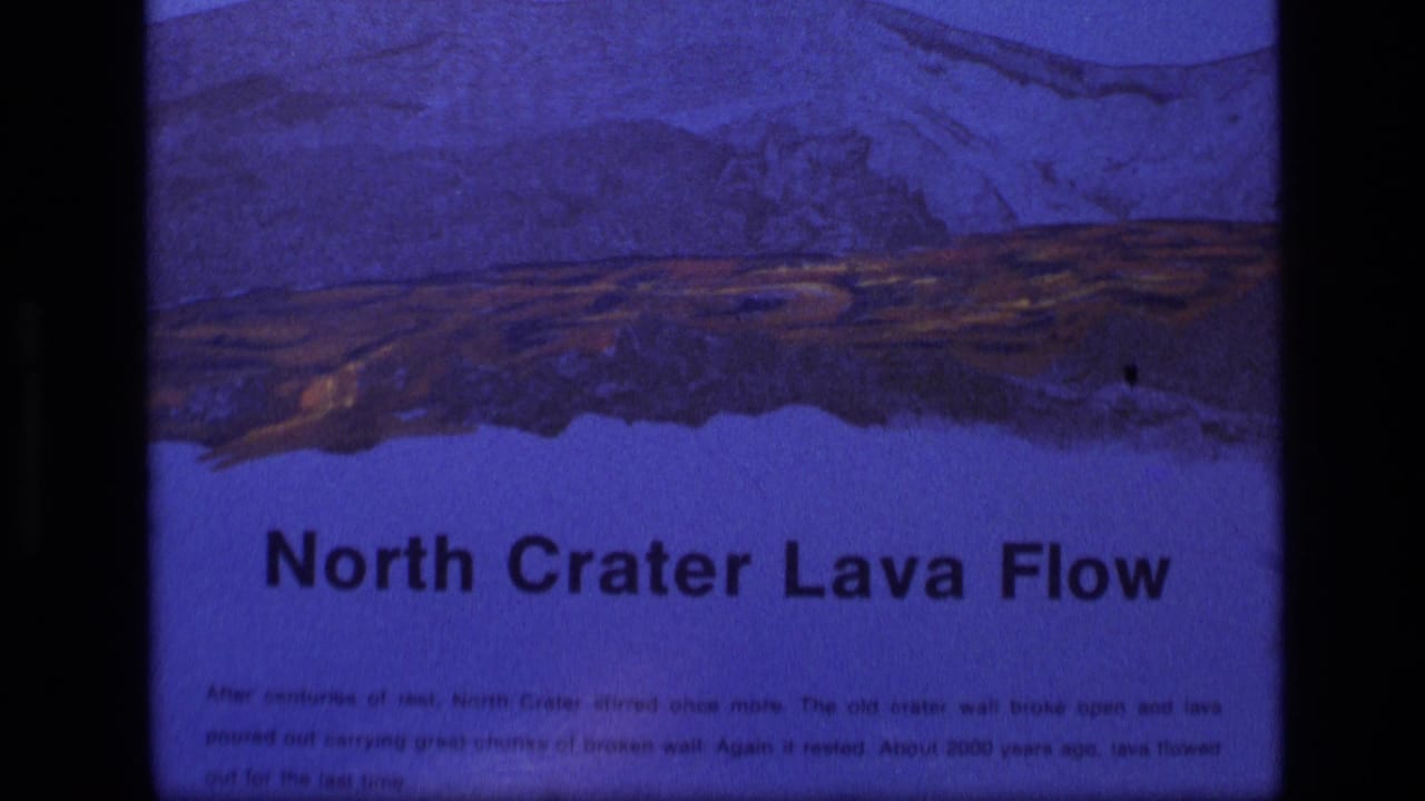 1972 Idaho 8mm frame holding on the North Crater Lava Flow sign, with blue cast, artwork, and visible film border.