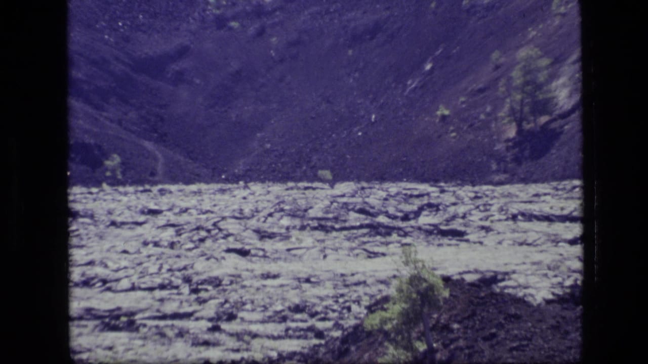 1972 8mm home-movie frame from Idaho showing a pale lake below dark rolling hills with sparse vegetation in front.
