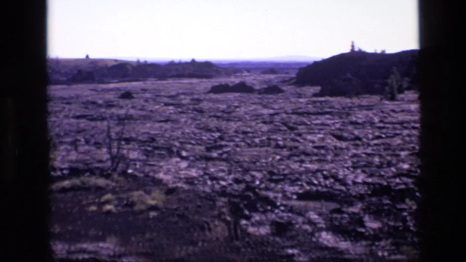 1972 Idaho 8mm frame showing an open volcanic plain, low ridges, sparse brush, and strong daylight.
