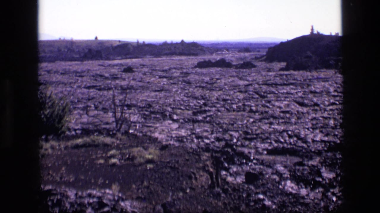 Rocky cracked ground stretches toward low hills under a pale sky.