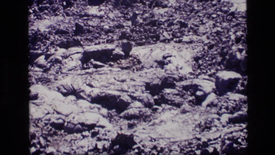 Close 1972 Idaho 8mm view of pale rocky ground, cracked textures, scattered stones, and high-contrast film exposure.