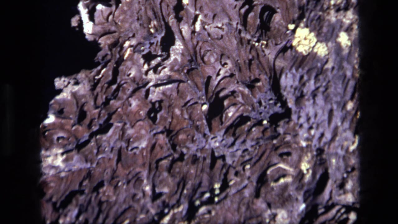 1972 Idaho 8mm frame with close-up rocky terrain, showing jagged cracks, raised ridges, and high-contrast sunlit detail.