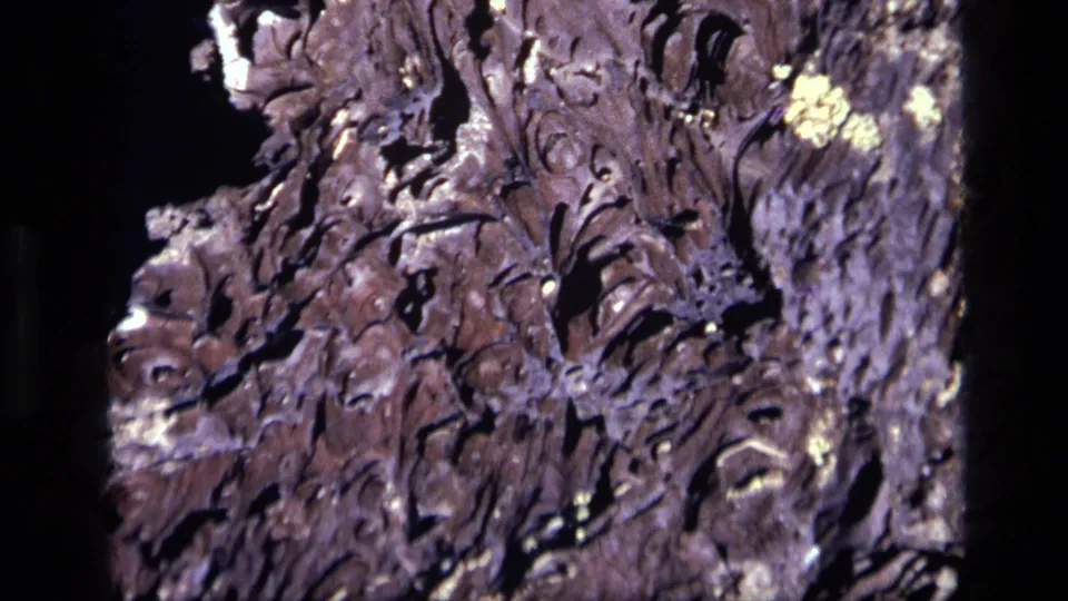 1972 Idaho 8mm frame with close-up rocky terrain, showing jagged cracks, raised ridges, and high-contrast sunlit detail.