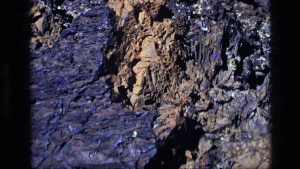 1972 Idaho 8mm frame showing a close-up of weathered rock layers with tan stone, dark bluish areas, and deep crevices.