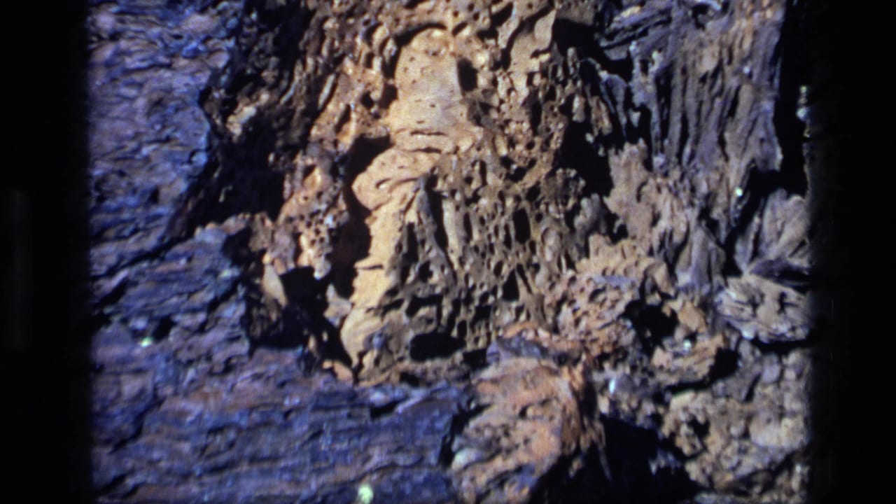 1972 Idaho 8mm frame with a closer view of tan, pitted rock against darker textured stone and shadowed cracks.