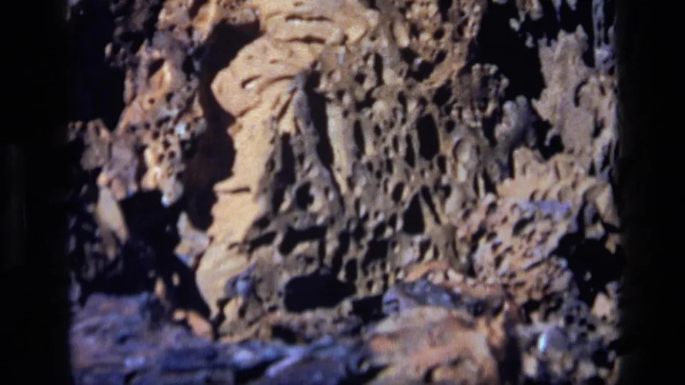 1972 Idaho 8mm frame ending on a tight close-up of rough eroded stone, dark recesses, and layered rock texture.