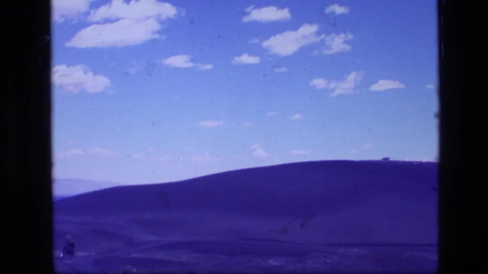 1972 Idaho 8mm frame showing a broad rounded hillside and open sky from a trail-side view.