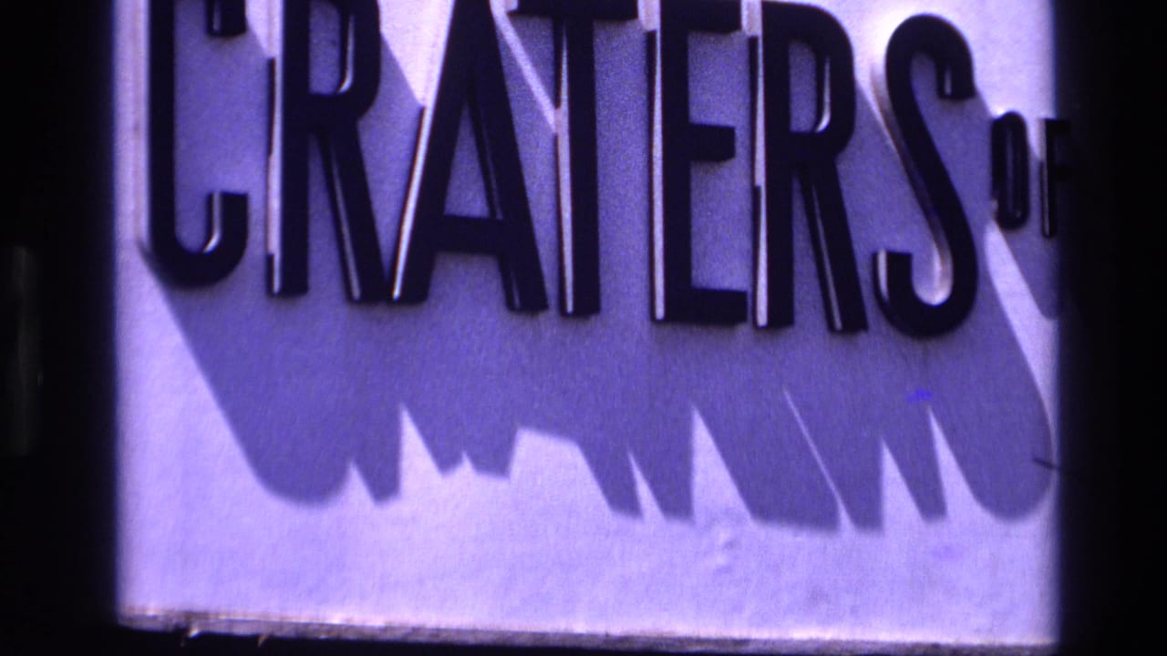 1972 Idaho 8mm frame showing a tight crop of the Craters of the Moon sign with black raised letters and strong shadows.
