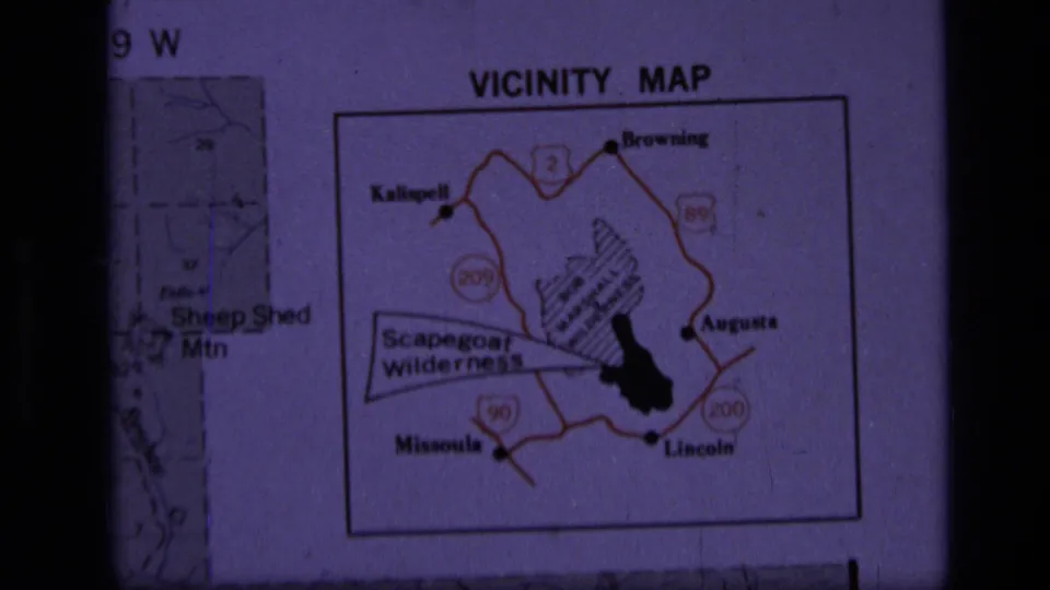 1973 8mm frame of a projected Scapegoat Wilderness vicinity map in Montana, with towns, roads, and a highlighted area visible.