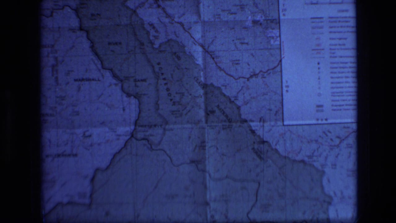 1973 8mm frame showing a blue-tinted projected map of Scapegoat Wilderness, Montana, with boundaries and a partial legend visible.