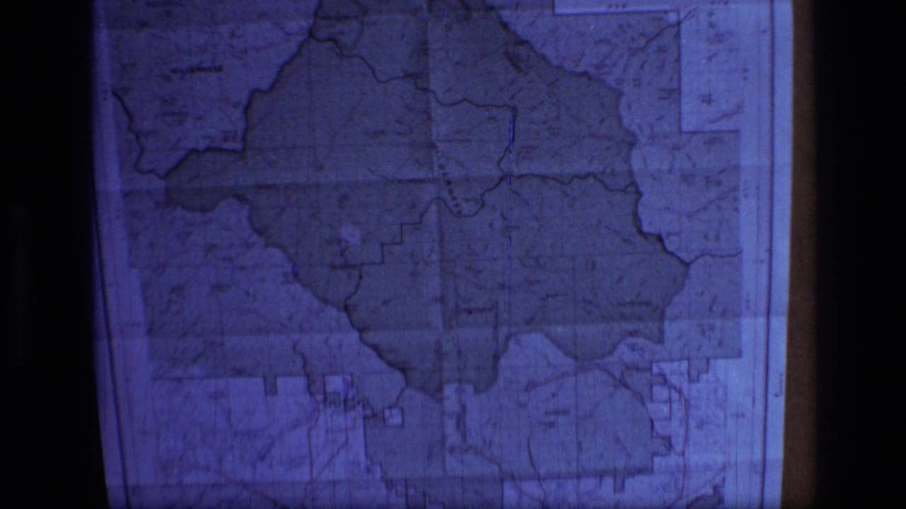 Blue-tinted close view of a framed topographic map with boundary outlines and grid markings.