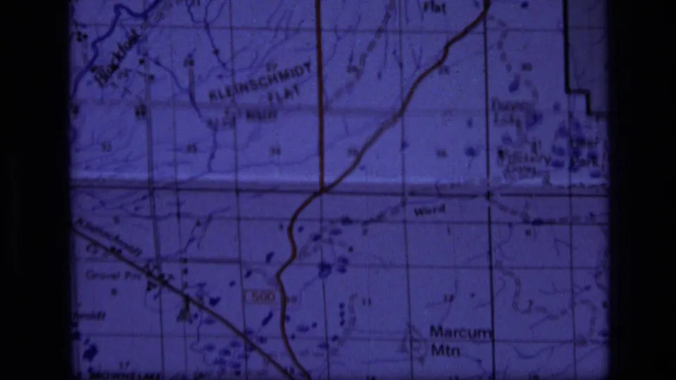 Close 8mm frame of a Montana topographic map with Kleinschmidt Flat, Marcum Mountain, road lines, and township-style grid markings.