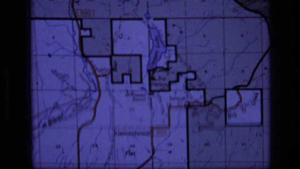 1973 home-movie frame showing a projected topographic map section with wilderness boundary lines and soft film grain.