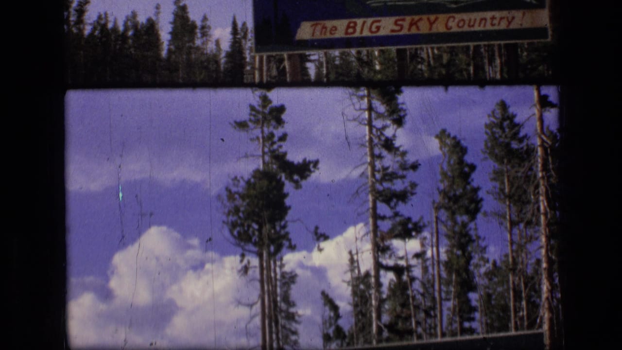 1973 Montana 8mm frame showing pine trees, clouds, and a partially visible Big Sky Country sign from a moving vehicle.