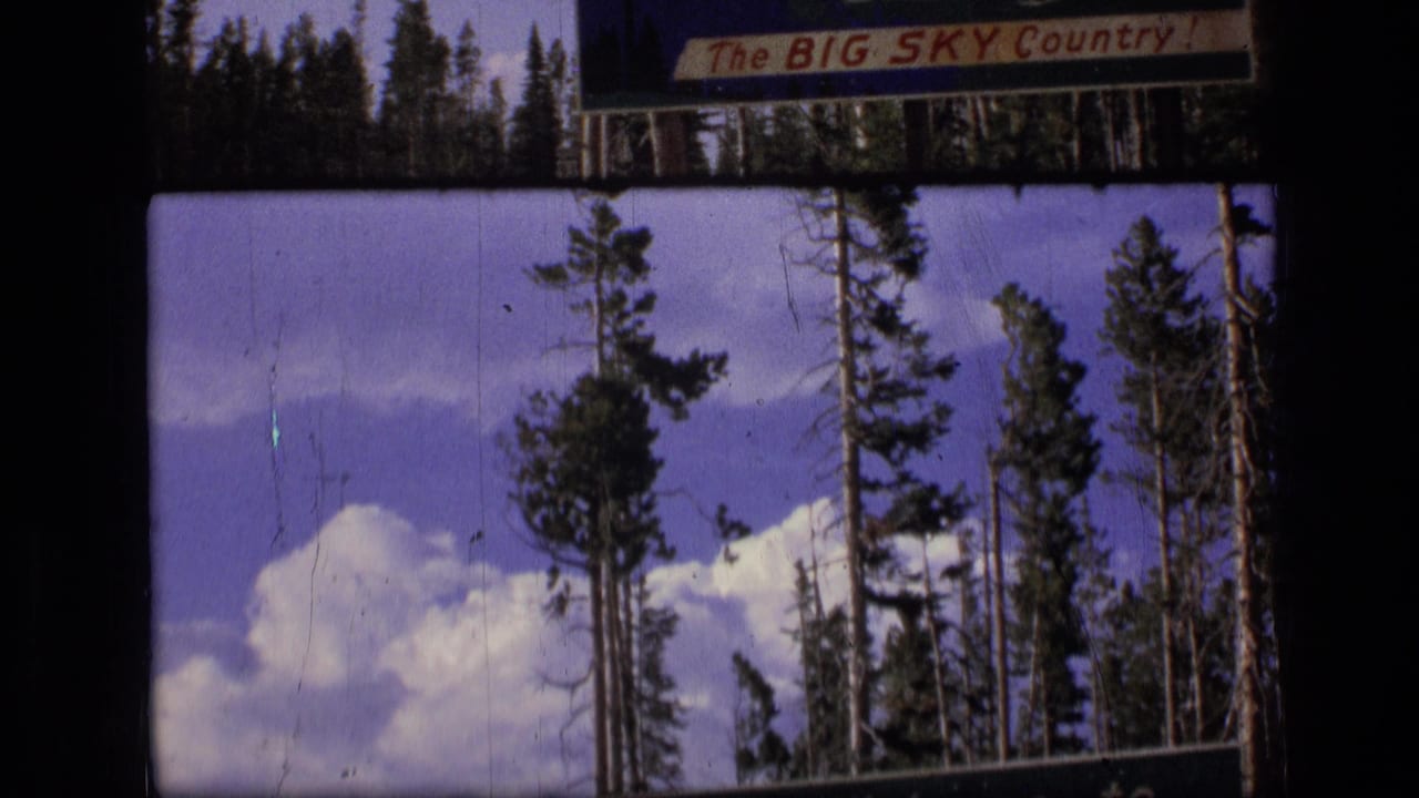 Evergreen trees and clouds beneath a roadside sign reading The BIG SKY Country.