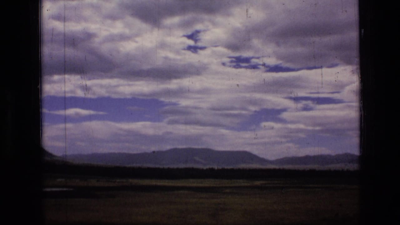 Distant hills beneath a partly cloudy sky, bordered by a dark vertical frame edge.