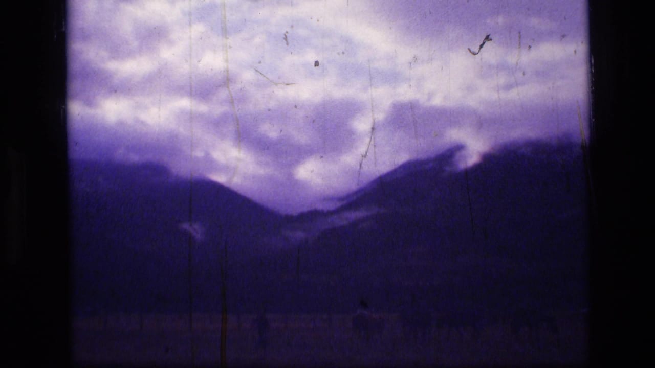 Dark mountain ridges beneath a cloudy purple-tinted sky on 8mm film.