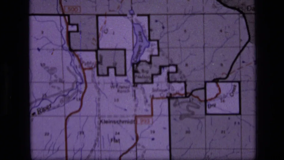 Close-up of a printed topographic map associated with the 1973 Scapegoat Wilderness footage, showing grid lines, roads, boundaries, and labels.