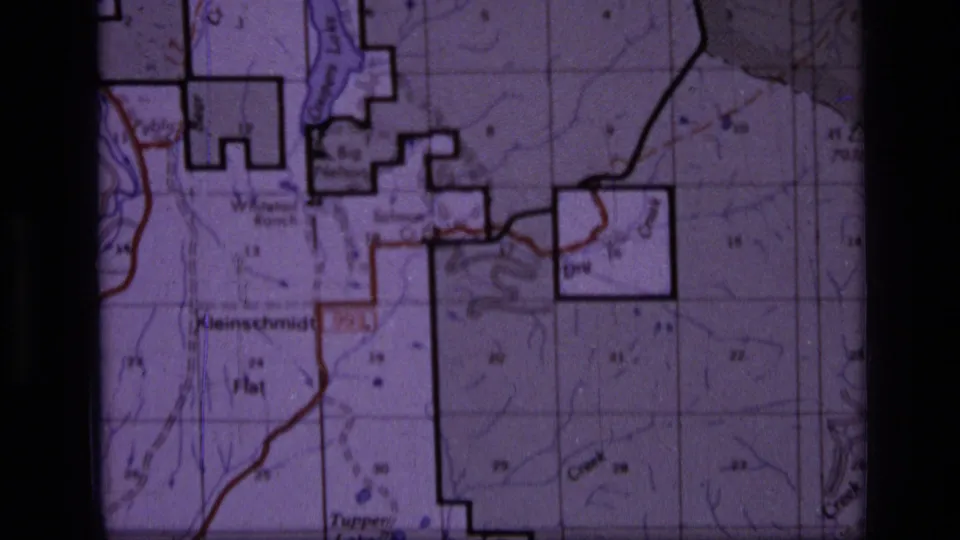 1973 8mm view of the Montana wilderness map with bold land-boundary outlines, contour detail, grid sections, and a red route line.