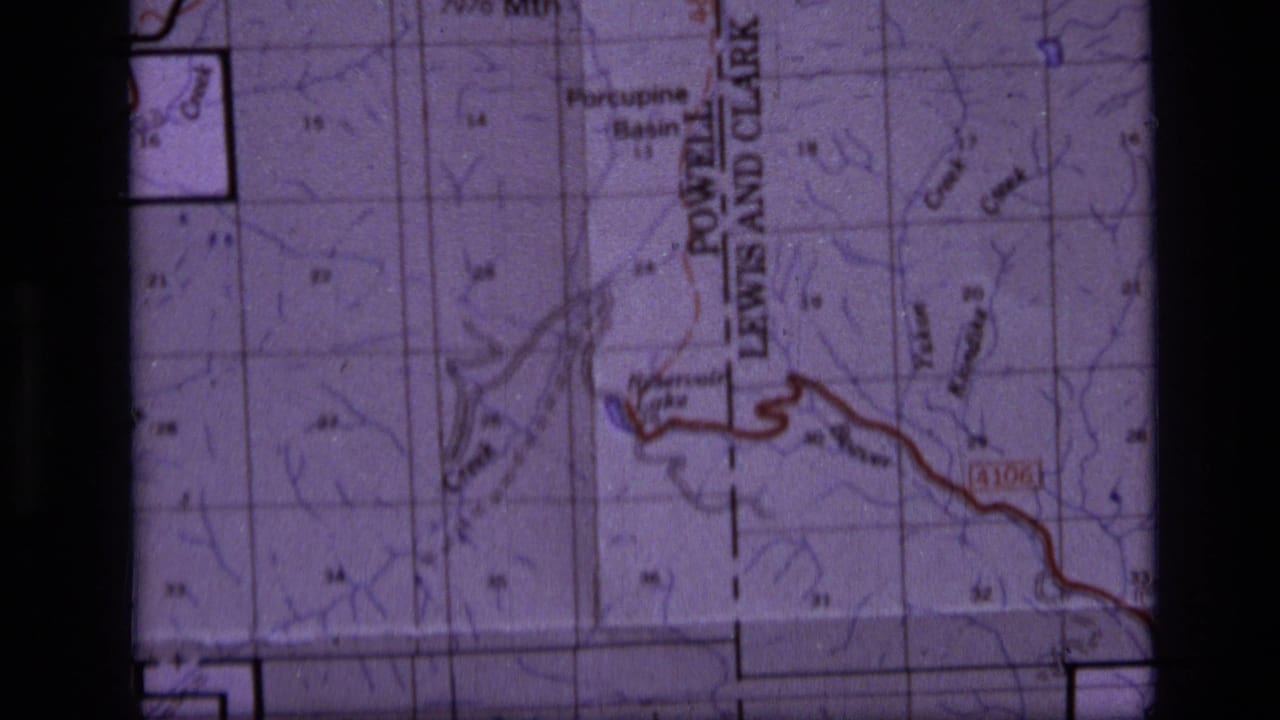 Close view of a topographic map with grid lines, labels, and a red route line.