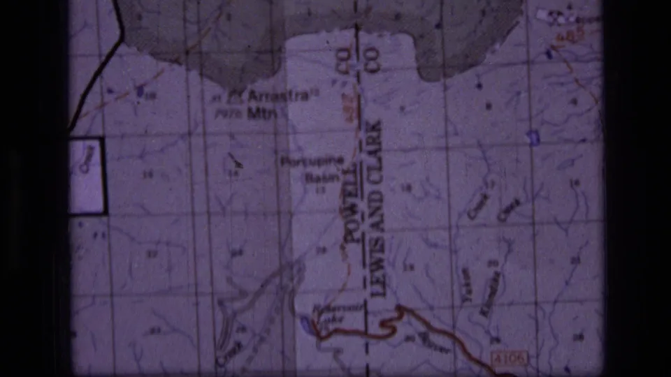 1973 8mm frame showing a Scapegoat Wilderness map with Porcupine Basin, Powell, grid lines, and red trail or road markings.