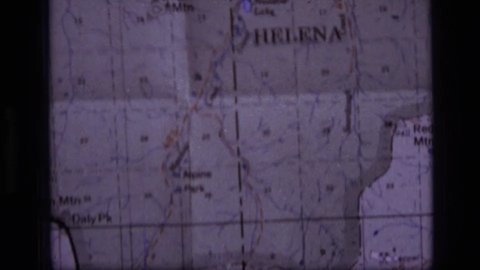 Soft 8mm frame of a Montana topographic map showing Helena and nearby wilderness labels, with grid lines and purple-tinted film texture.